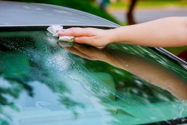 Vrouwen drogen het oppervlak van de auto met een microvezeldoek na het wassen droog af.