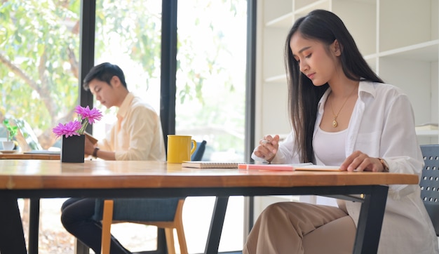 Vrouwen en mannen werken in het café, ze zitten op een sociale afstand.