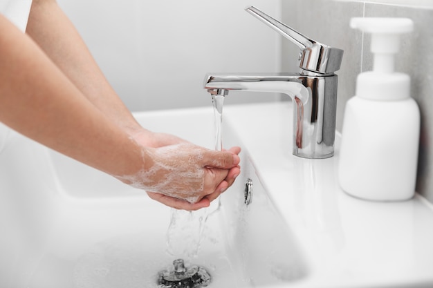 Vrouwen gebruiken zeep en handen wassen onder de waterkraan voor het voorkomen van coronavirus.