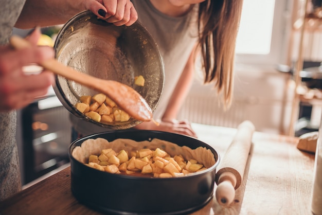 Vrouwen gietende appel die in bakvorm vullen