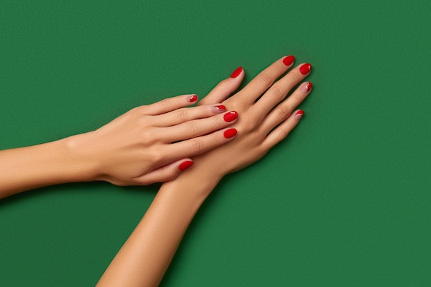 Vrouwen handen met trendy kerst rode manicure op groene achtergrond