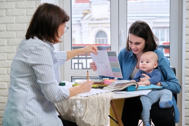 Vrouwen interieurontwerper en klant met baby die stoffen en materialen kiest.