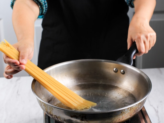 Vrouwen koken spaghetti in pan kokend water in de keuken. Thuis kookproces en voorbereiding