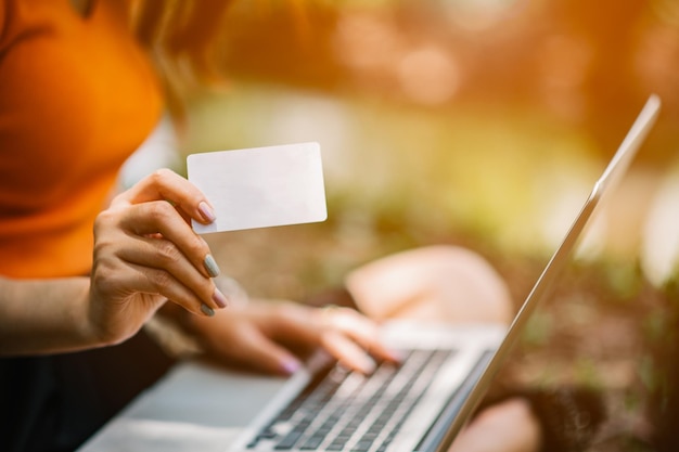 Vrouwen kopen online met creditcards in het park. Online winkelen. Online betalen. creditcard gebruiken voor online winkelen.