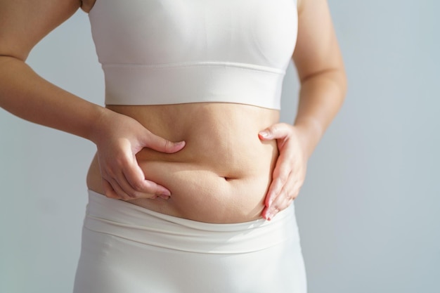 Vrouwen lichaamsvet buik Zwaarlijvige vrouw hand met overmatig buikvet dieet levensstijl concept om de buik te verminderen en een gezonde maagspier vorm te geven