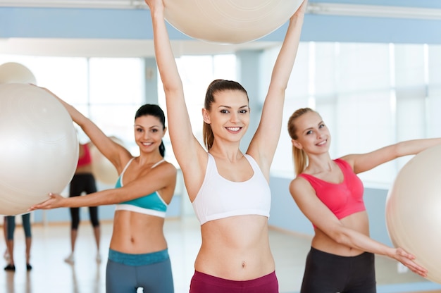 Vrouwen met fitnessballen. Drie mooie jonge vrouwen in sportkleding