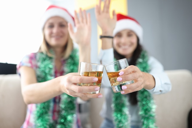 Vrouwen met nieuwjaarsversieringen en met kerstmutsen houden glazen alcohol in hun handen en zwaaien