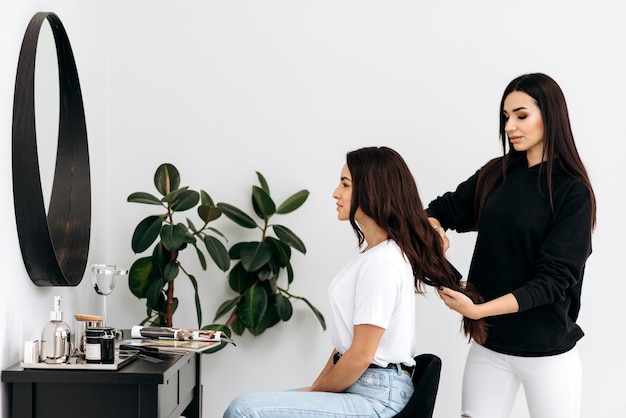 Vrouwen met stijlvol haar dat lacht terwijl ze kappers zijn en verzorgingsbehandelingen Master styling krullend haar voor de klant Professionele schoonheids- en modeservice voor beroepen