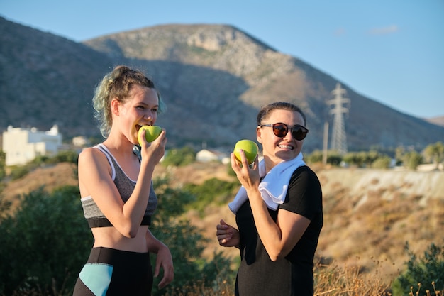 Vrouwen moeder en tienerdochter groene appels eten op aard