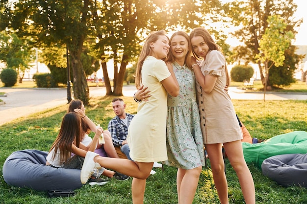 Vrouwen omhelzen elkaar Groep jongeren hebben een feestje in het park op zomerdag