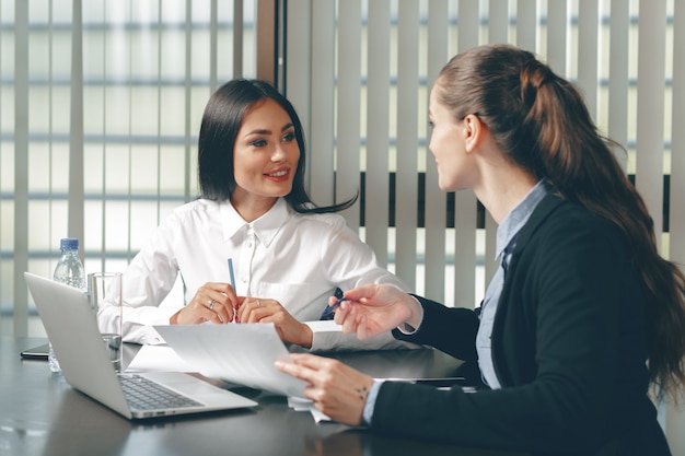 Vrouwen op zoek financiële documenten in de laptop aan tafel