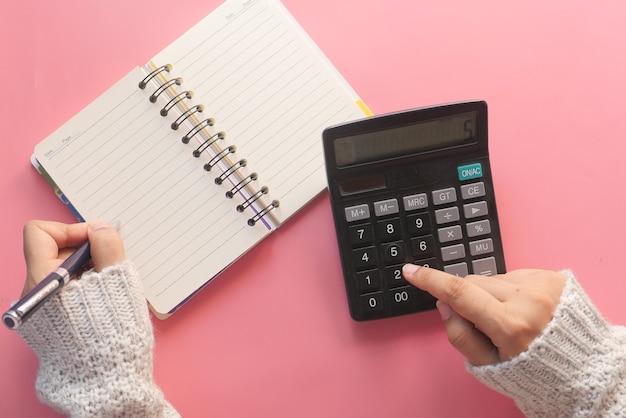 Vrouwen overhandigen met behulp van calculator op roze achtergrond