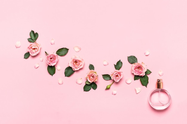 Foto vrouwen parfum fles en rozen bloemen op roze achtergrond minimale schoonheid concept kopieer ruimte