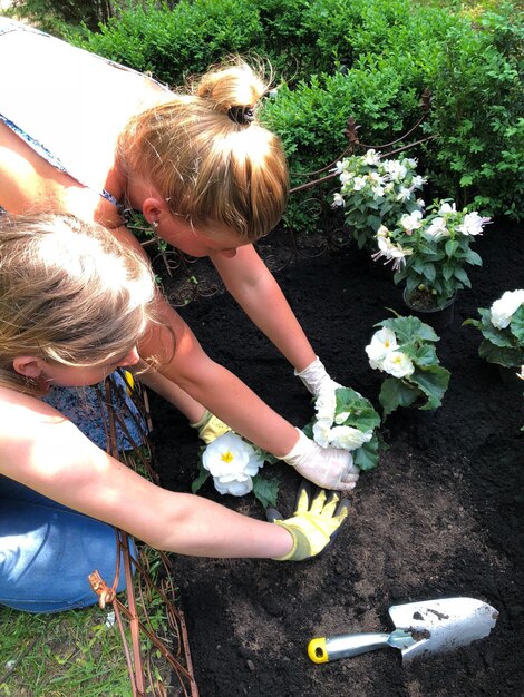 Foto vrouwen planten bloemen in de tuin