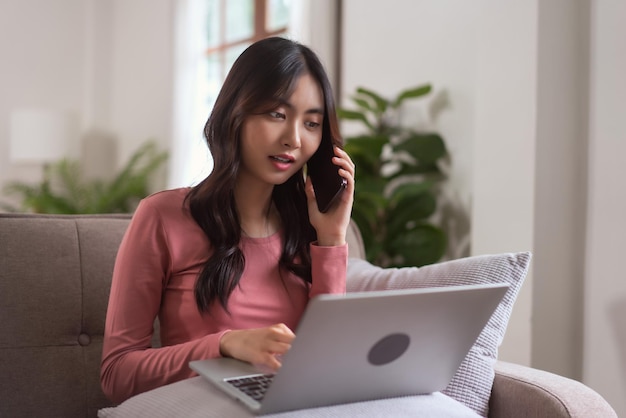 Vrouwen praten op smartphone en typen zakelijke gegevens op laptop terwijl ze thuis in levensstijl werken