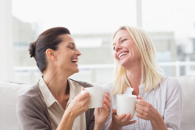 Vrouwen roddelen terwijl ze koffie drinken in de woonkamer