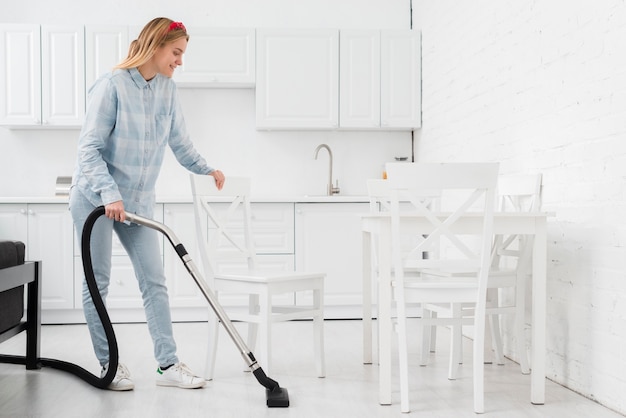 Vrouwen schoonmakend huis met vacuüm
