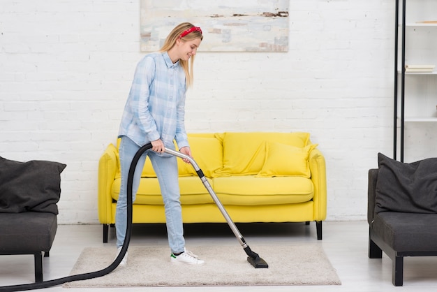 Vrouwen schoonmakend tapijt met vacuüm