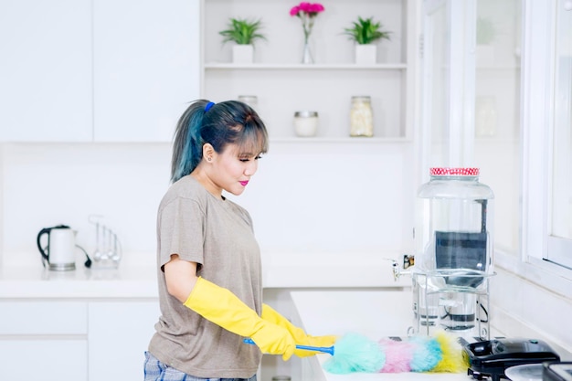 Vrouwen schoonmakende lijst met een stofdoekborstel in keuken