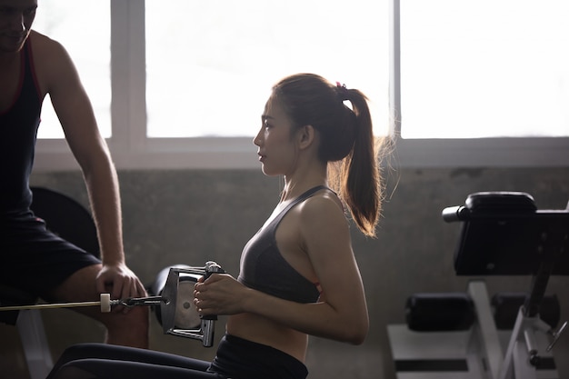 vrouwen trainen gewichtheffen haar lichaam met trainer in fitness