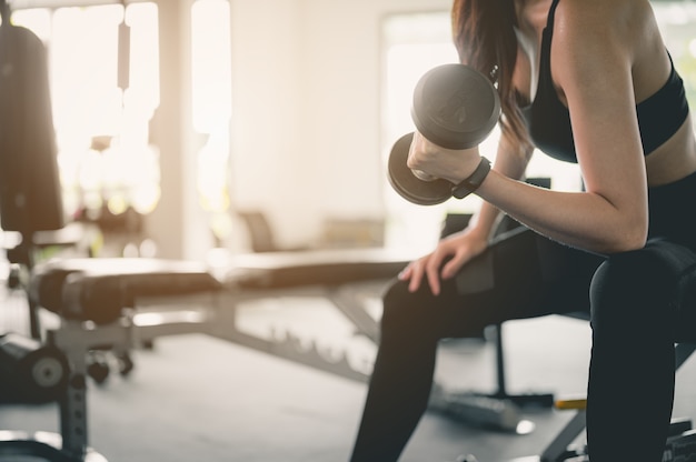 Vrouwen trainen met dumbbells in de indoor gym voor een goede gezondheid bij zonsondergang Fitness workout