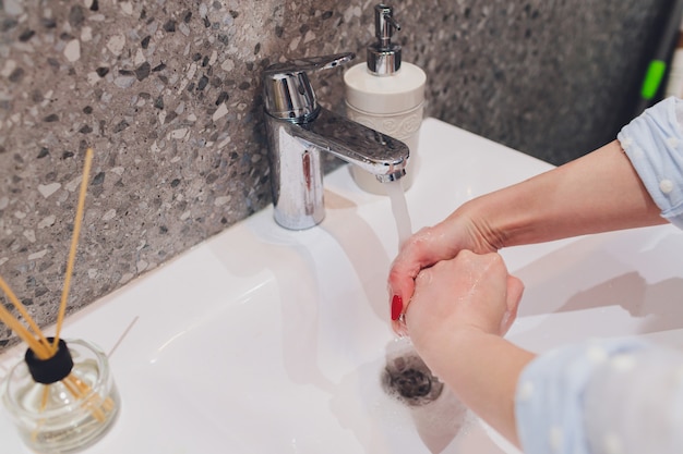 Vrouwen wassen haar handen in de gootsteen