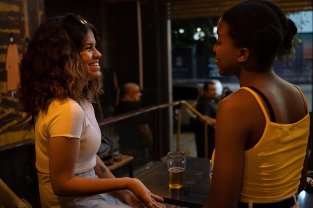 Vrouwen zitten aan tafel in de pub praten en lachen. Multi-etnisch concept.