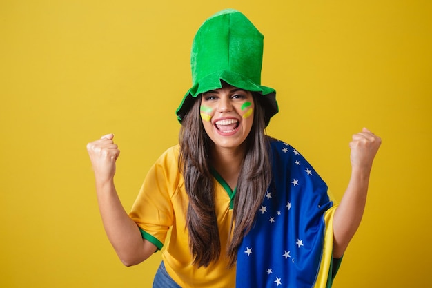 Vrouwenaanhanger van het WK 2022 van Brazilië, gekleed in typische fanoutfit om naar het spel braziliaanse vlag en groene hoed te feesten Schreeuwend doel