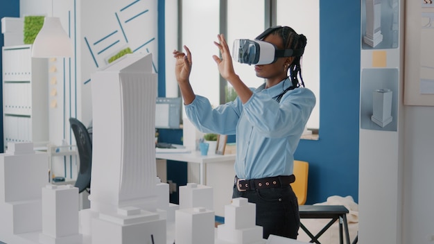 Vrouwenarchitect die een vr-bril draagt om de bouwlay-out en het bouwmodel te ontwerpen. Bouwer die vastgoedproject plant met virtual reality-headset en maquette. Architectuurplan