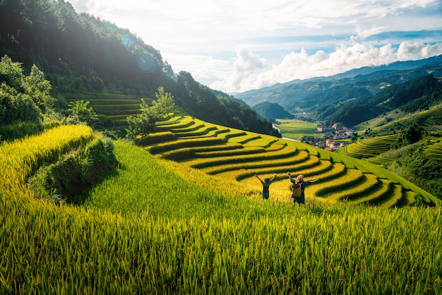 Vrouwenboer en dochter die wapen op padievelden opheffen terrasvormig bij zonsondergang in Vietnam.