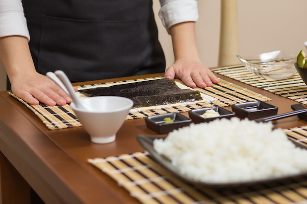 Vrouwenchef-kok klaar om japanse sushibroodjes te bereiden