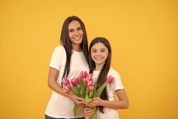 Vrouwendag gelukkige moeder en dochter met tulpenbloemen op gele achtergrond