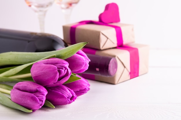 Vrouwendag. geschenken met bloemen en wijn op witte muur