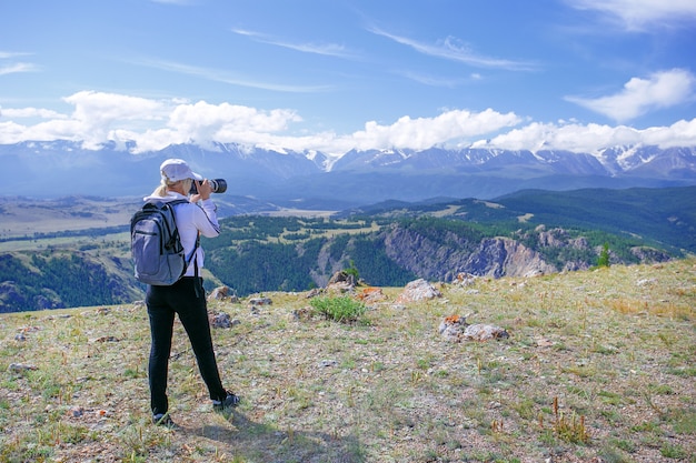 Vrouwenfotograaf die foto nemen bij bergpiek. Wandelaarvrouw met rugzak en camera die foto op bergpiek maken.