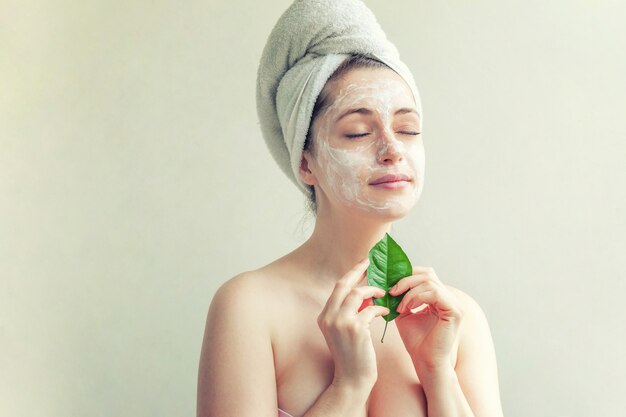 Vrouwengezicht met groen blad en room of voedend masker