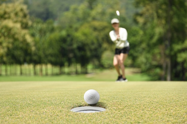 Vrouwengolfspeler die na een golfbal op een groen golf toejuichen