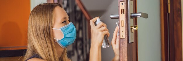 Vrouwenhand brengt ontsmettingsmiddel aan op de deurklink die de deurklink schoonmaakt met alcoholspray voor