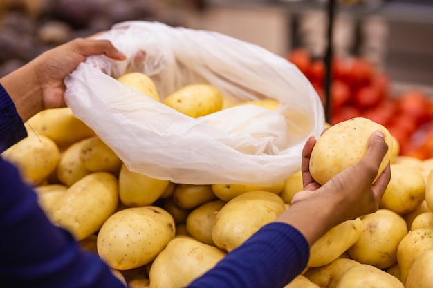 Vrouwenhand die aardappelen op de markt selecteert