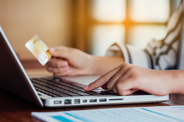 Vrouwenhand die creditcard houden en laptop met behulp van.