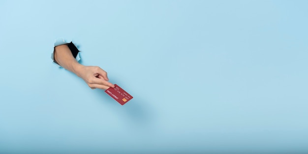 Vrouwenhand die creditcard op blauwe bannerachtergrond houden. Panoramisch beeld