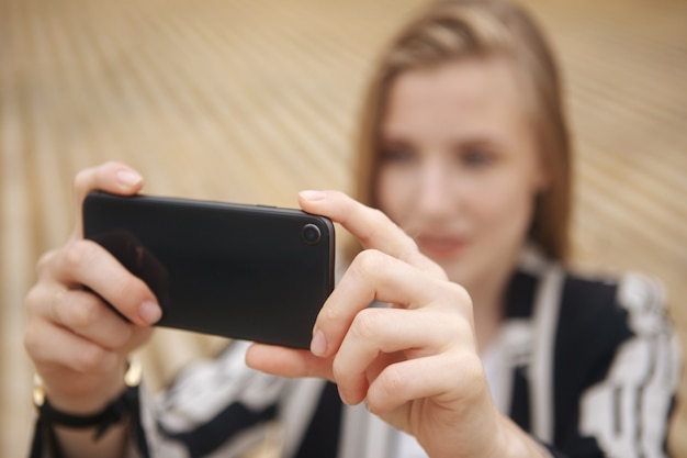 Vrouwenhand die foto van de stad nemen met een smartphone. Sluit omhoog van de handen van de vrouw. Mobiele telefoon. Telefoon. Mobiliteit en modern lifestyle concept. Mooie lucht. Jong meisje dat foto's maakt van het landschap