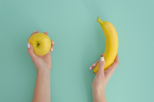 Vrouwenhand die gele kleine appel en tropische banaan houden