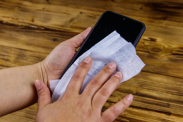 Vrouwenhand die het smartphonescherm schoonmaakt met een nat doekje