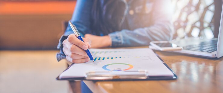 Vrouwenhand die op grafieken en grafieken schrijven die resultaten met een pen tonen.