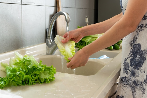 Vrouwenhand die sla in keuken wassen