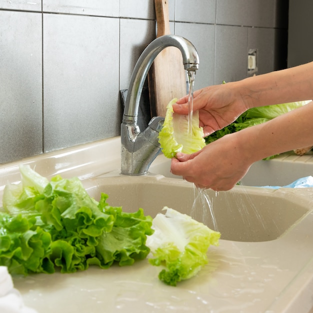 Vrouwenhand die sla in keuken wassen