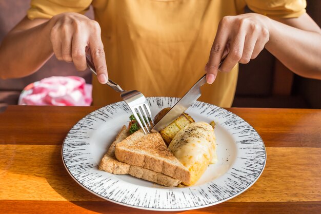 Vrouwenhand die witte plaat met omeletaardappel, tomatenpeterselie en feta-kaas houden