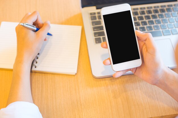 vrouwenhand gebruikt de telefoon op het lege scherm en schrijfblok