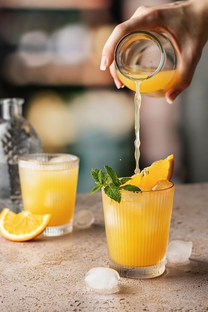Vrouwenhand giet sap in een cocktailglas gevuld met een alcoholische drank in pub Alcoholische frisdrank in nachtclub