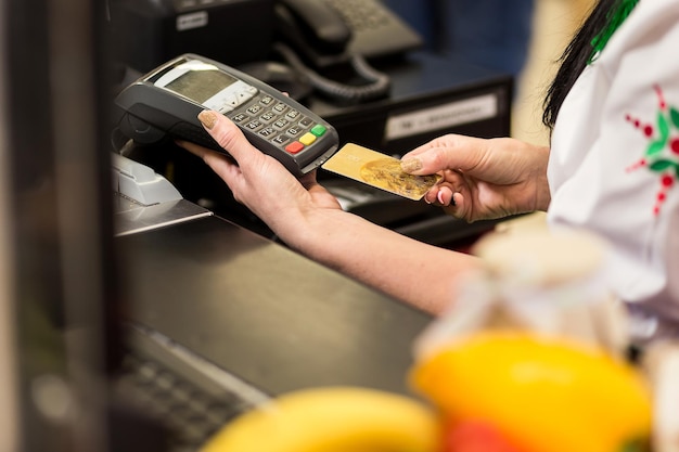 Vrouwenhand met creditcard veeg door terminal te koop in markt winkel- en winkelconcept